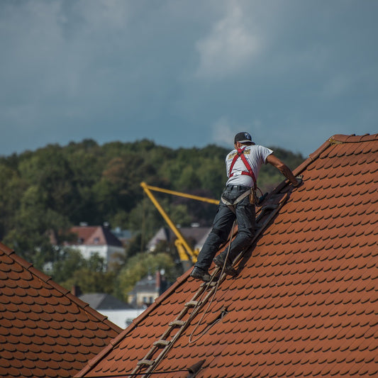 Ein Dachdecker klettert auf ein Dach